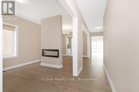 A spacious room with a fireplace and wooden flooring.