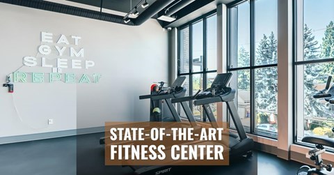 A fitness center with a wall that says "Eat Gym Sleep Repeat".