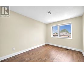 A room with a window showing a view of a house and trees outside.