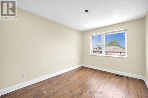 A room with a window showing a view of a house and trees outside.