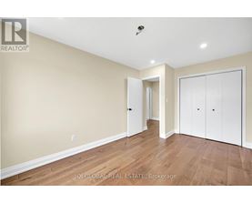 A spacious room with wooden flooring and white walls.