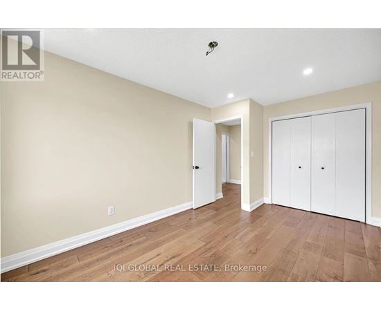 A spacious room with wooden flooring and white walls.