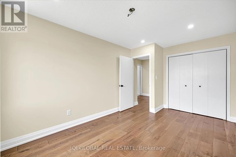 A spacious room with wooden flooring and white walls.