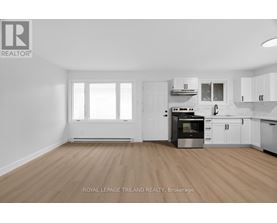 A kitchen with white cabinets and a wooden floor.