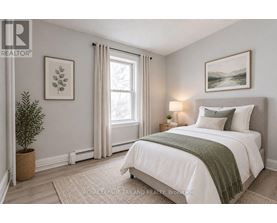 A bedroom with a large bed and a window with curtains.