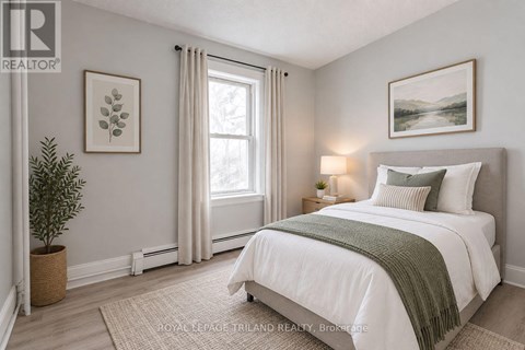 A bedroom with a large bed and a window with curtains.