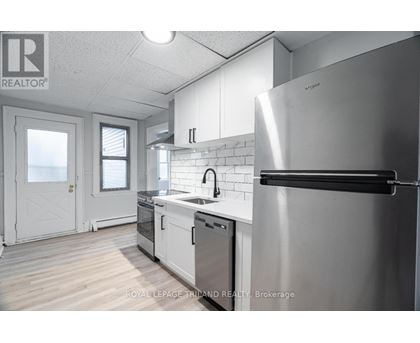 A modern kitchen with a stainless steel refrigerator and white cabinets.