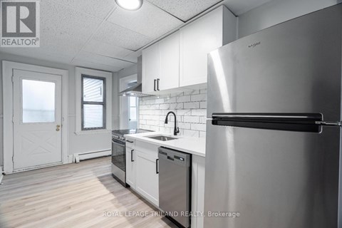A modern kitchen with a stainless steel refrigerator and white cabinets.