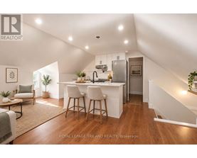 A well-lit, spacious kitchen and dining area with a breakfast bar and a staircase leading to the upper level.