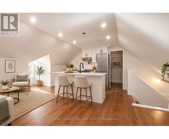 A well-lit, spacious kitchen and dining area with a breakfast bar and a staircase leading to the upper level.