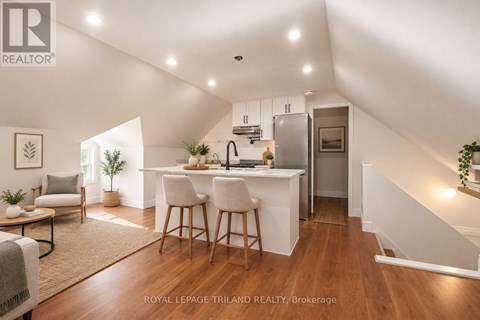 A well-lit, spacious kitchen and dining area with a breakfast bar and a staircase leading to the upper level.