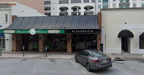A car is parked in front of a building with a sign that reads "Altagracia".