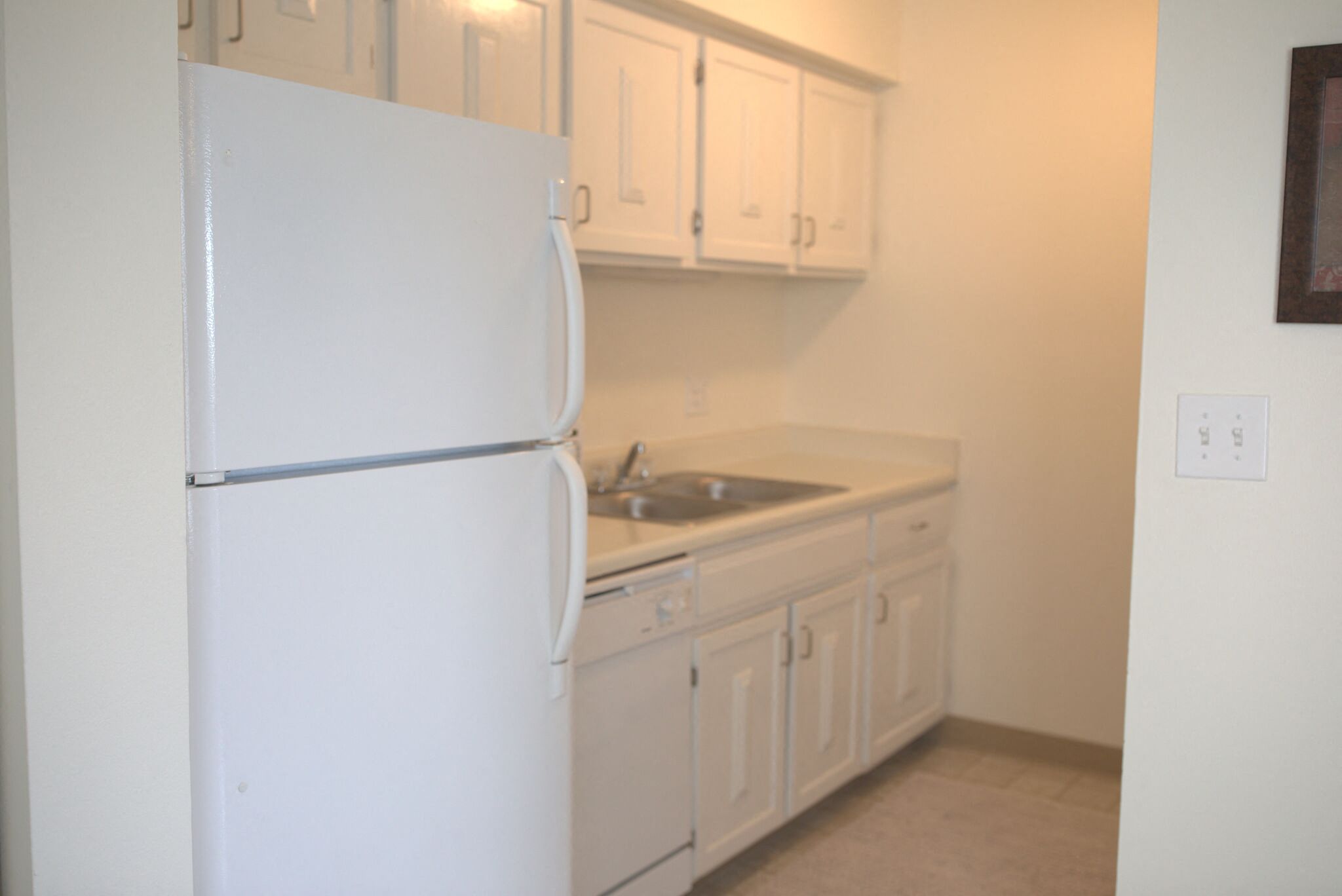 a kitchen with white cabinets and a white refrigerator and sink