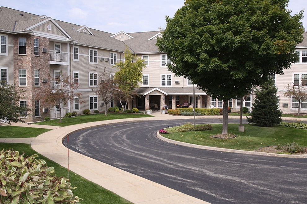 a street in front of an apartment building with a tree