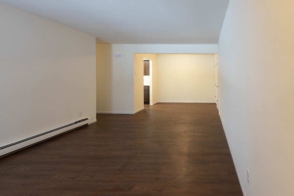 a empty living room with wood floors and white walls