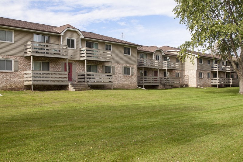 an exterior view of an apartment building with a green lawn