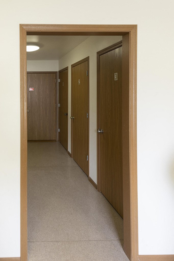 an empty hallway with doors to three bathroom doors