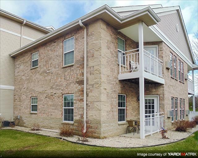 a brick house with a balcony and a yard
