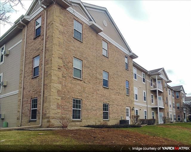 a brick apartment building with a yard in front of it