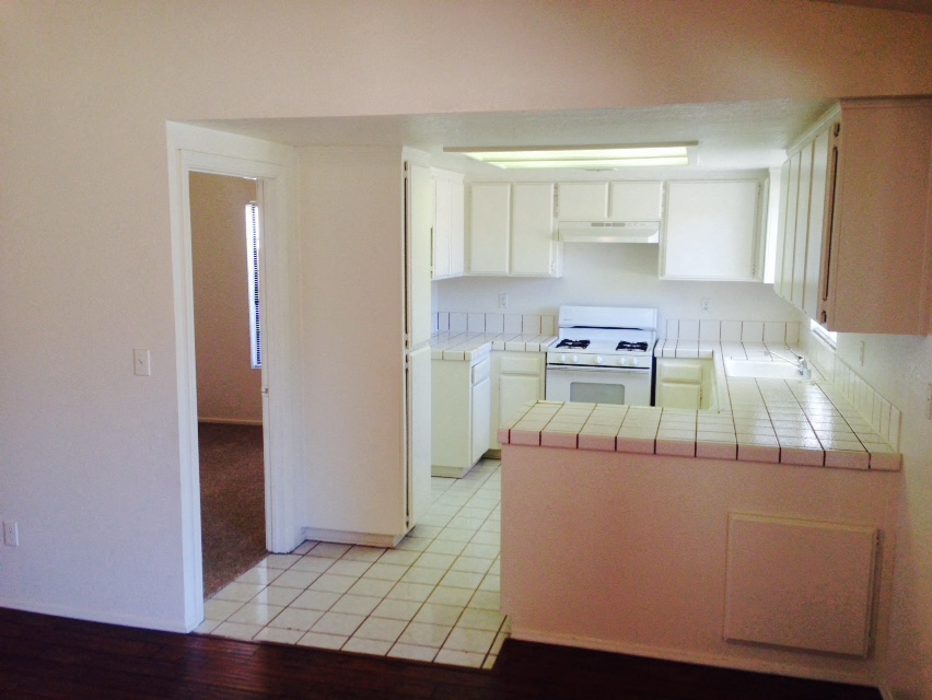 A kitchen with white cabinets and a white stove.