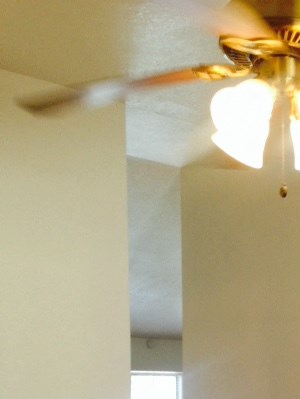 A room with a ceiling fan and a door.