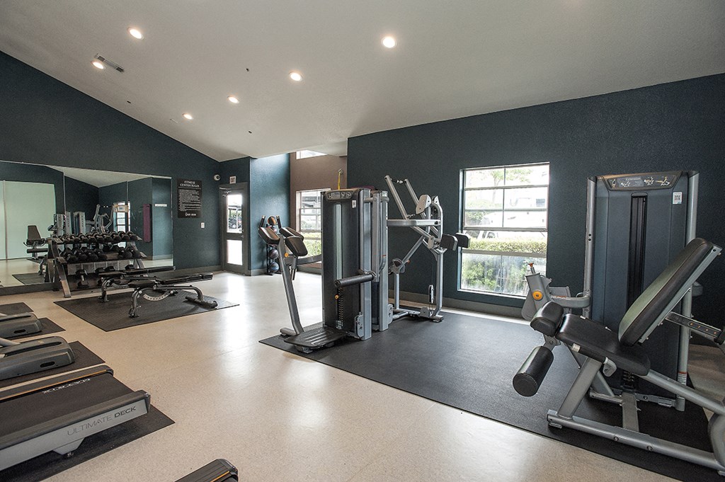a gym with weights and cardio equipment and a window