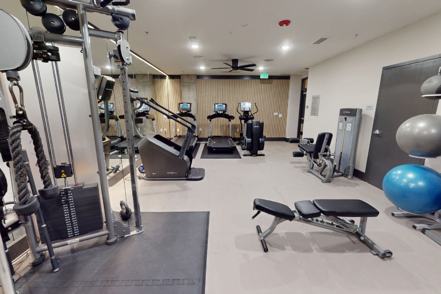 A gym with a variety of equipment including a treadmill, weights, and a bench press.