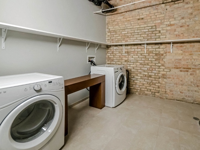 a washer and dryer in a laundry room with a brick wall