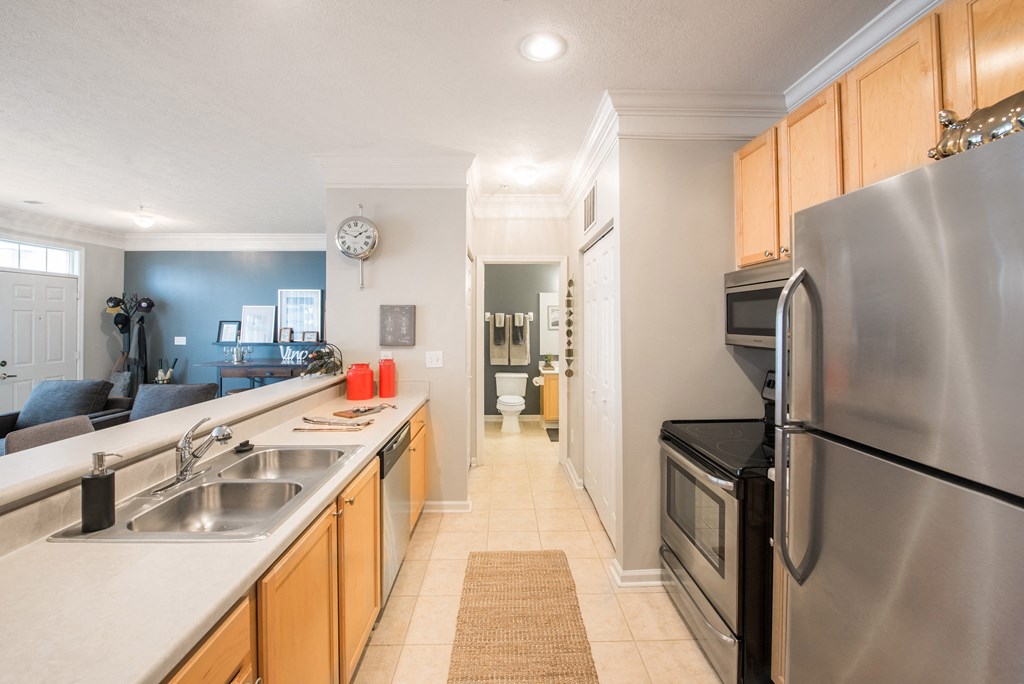a kitchen with stainless steel appliances and a long counter with a sink and a refrigerator