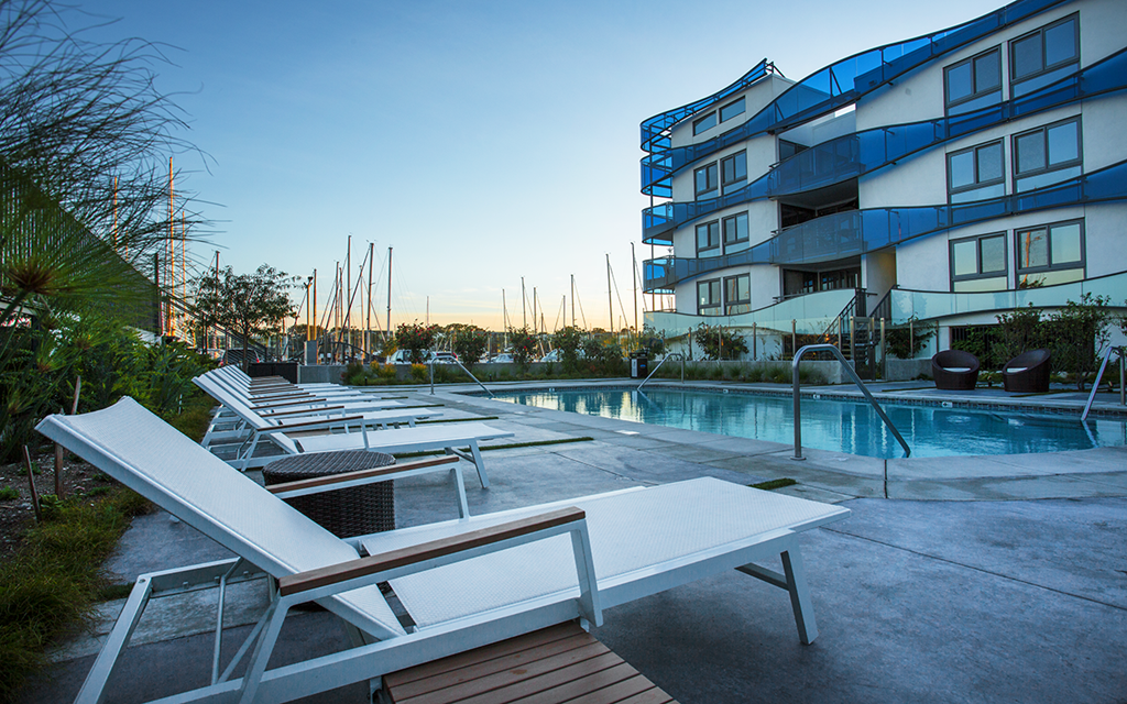 a pool with chairs in front of an apartment building