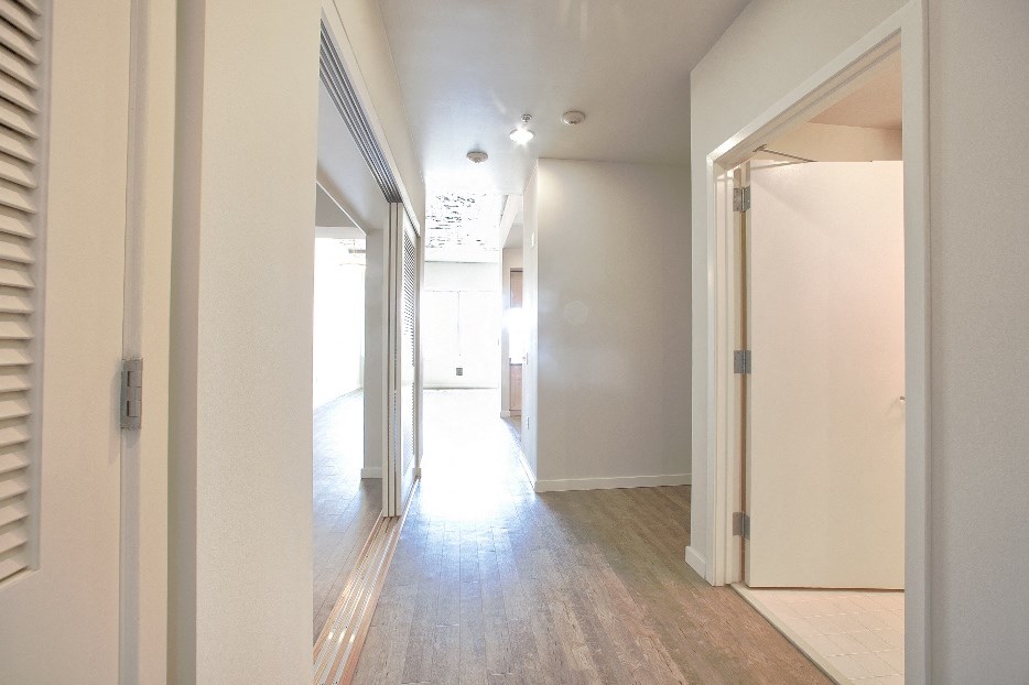 the hallway of a home with white walls and a wood floor