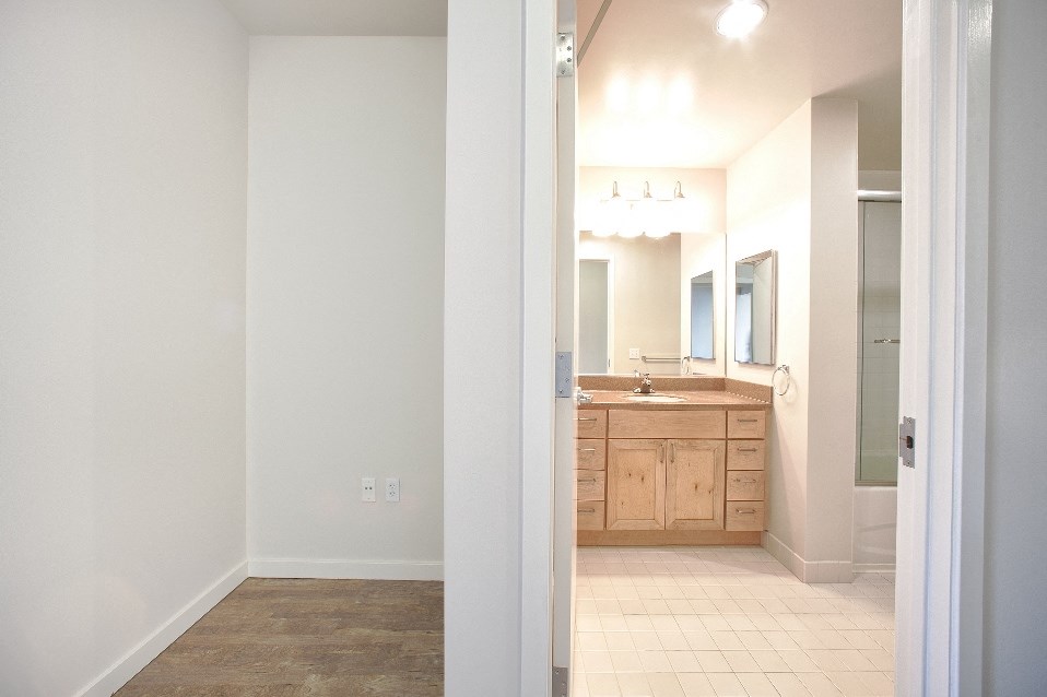 an open doorway into a bathroom with a sink and mirror