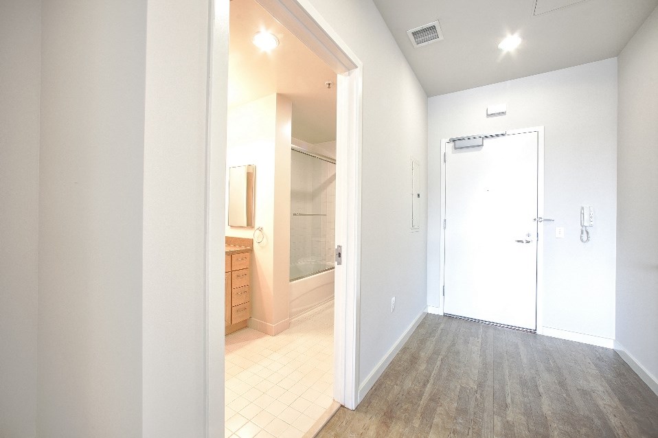 an empty hallway with a bathroom and a door to a closet