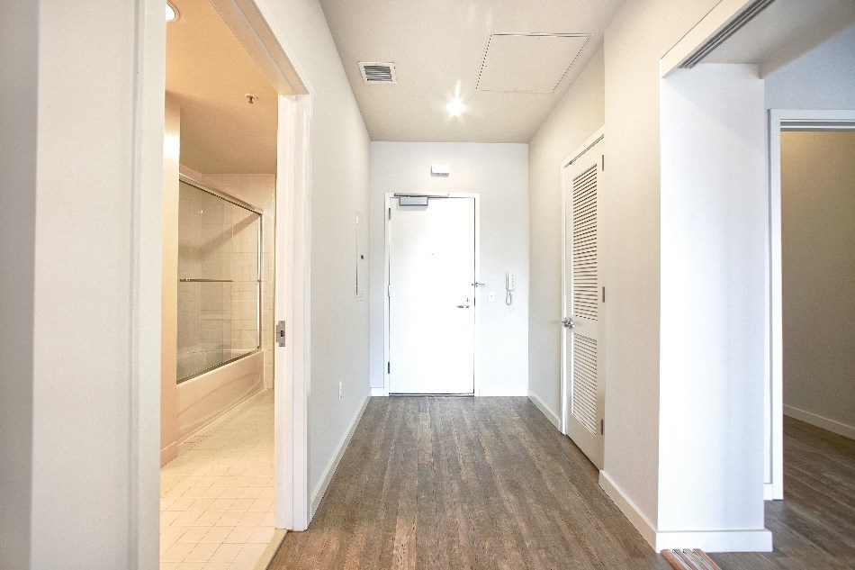 a hallway with white walls and wood floors and a white door