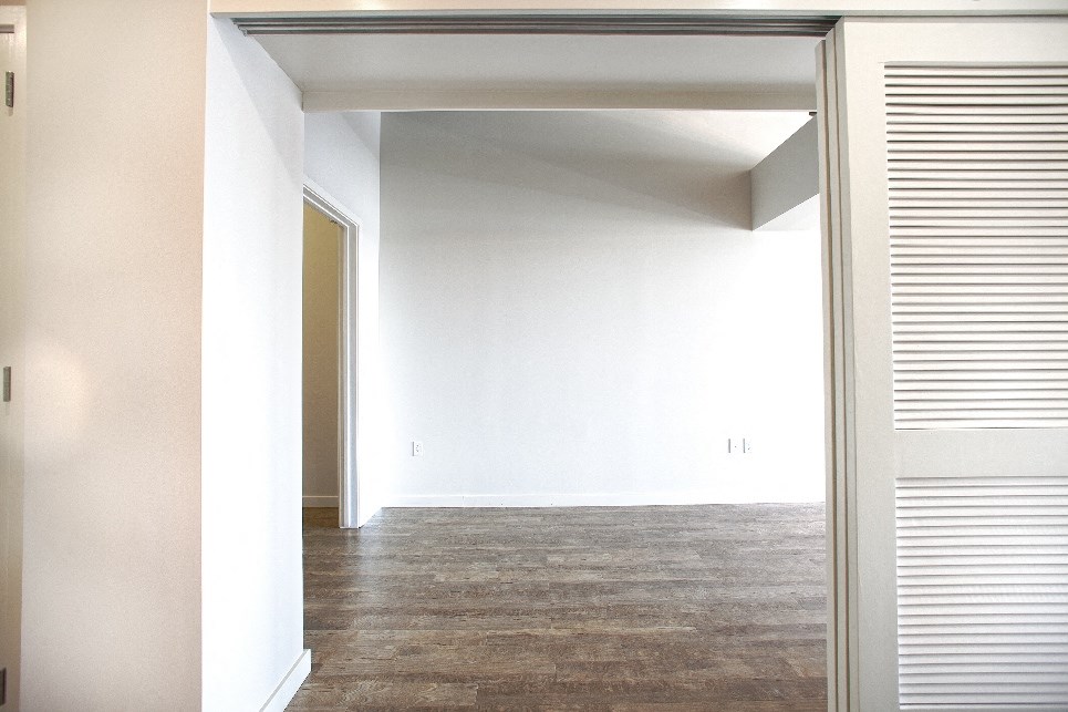 an empty living room with white walls and a wood floor