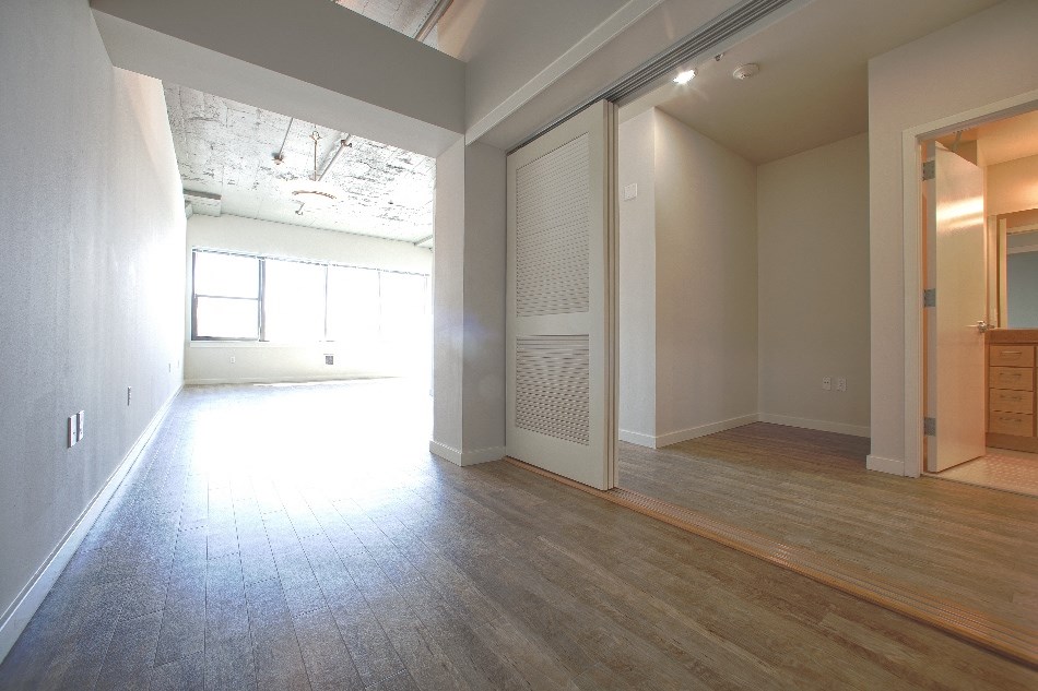 an empty living room with a wood floor and a door