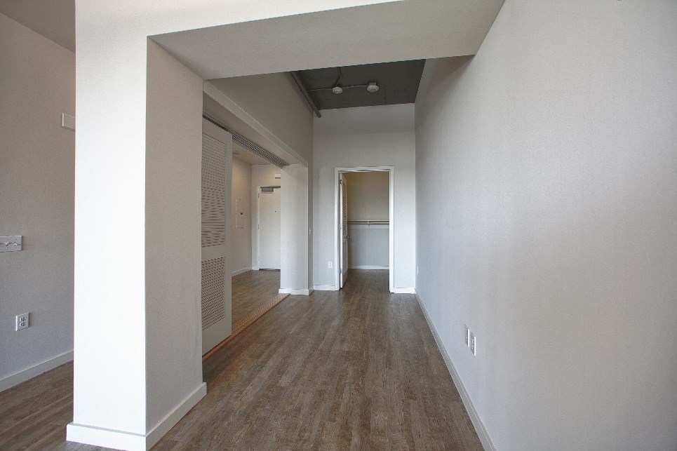 a living room and hallway with white walls and wood floors