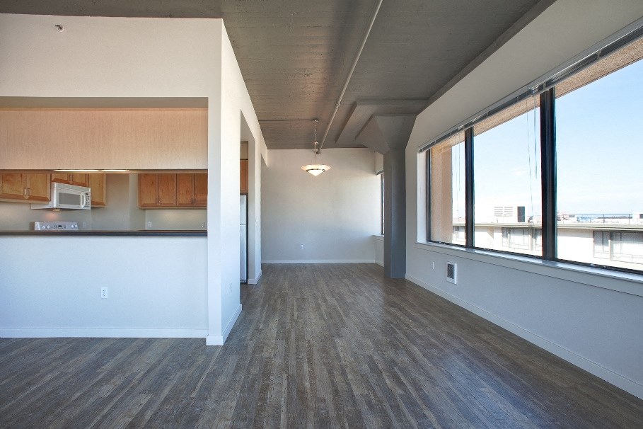 an empty living room with wood flooring and large windows