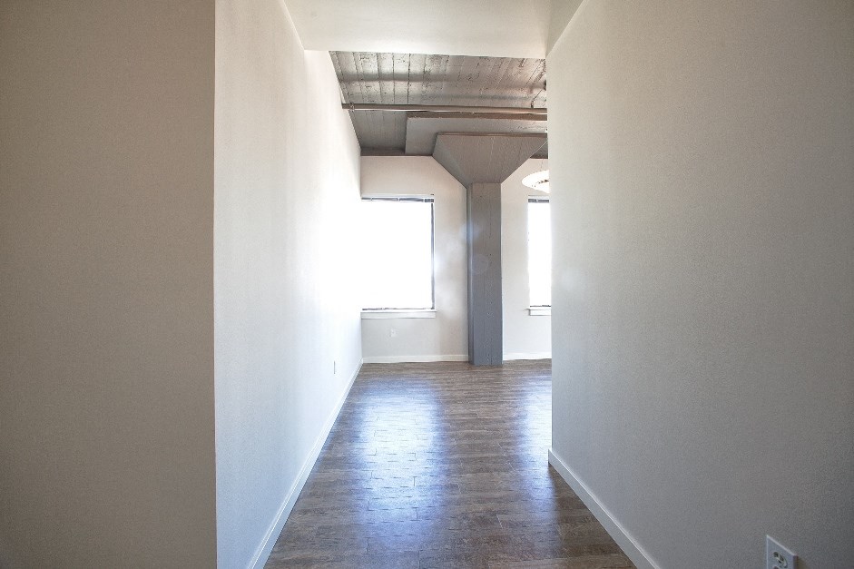 a view from the hallway of a house with white walls and wood floors