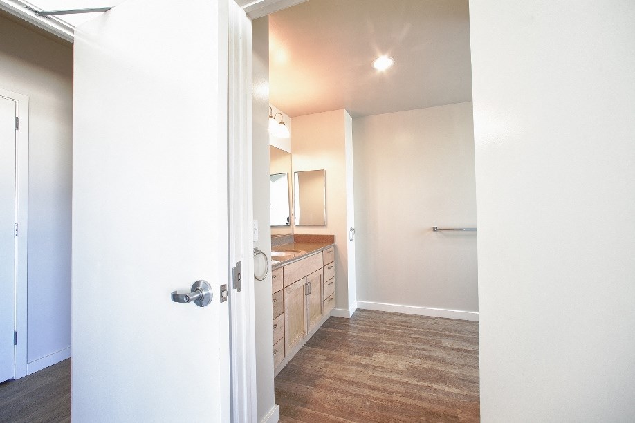an open door leading to a bathroom with a sink and a mirror