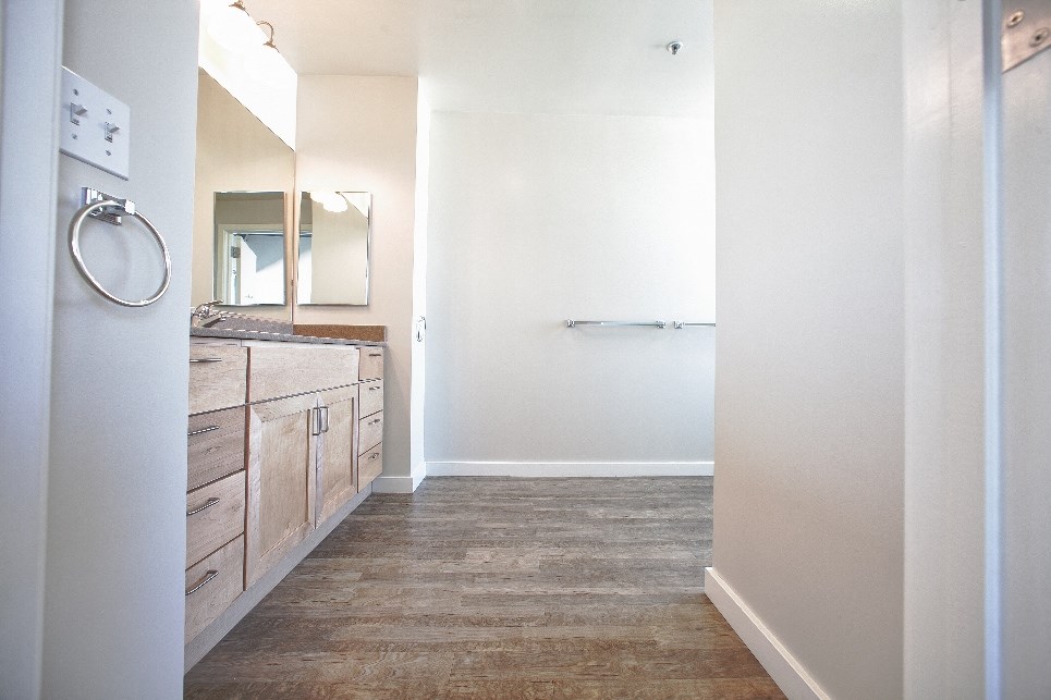 an empty bathroom with wooden cabinets and a large mirror