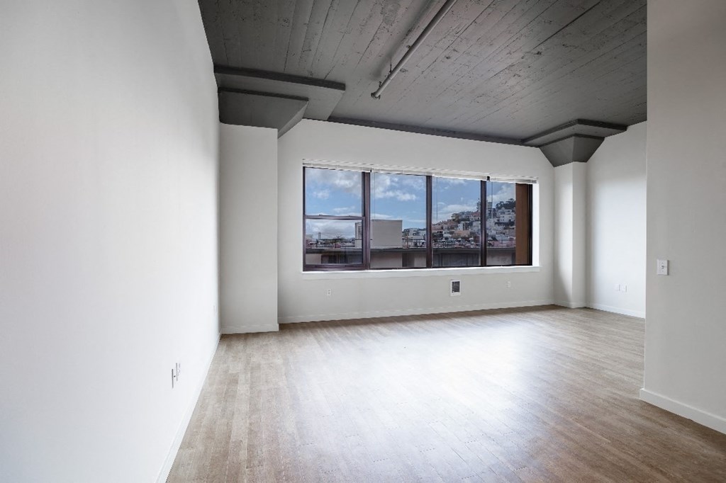 the living room of an empty apartment with a large window