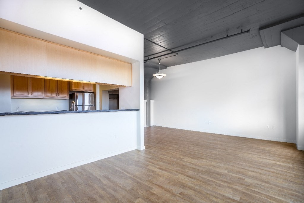 an empty living room and kitchen with a wood floor
