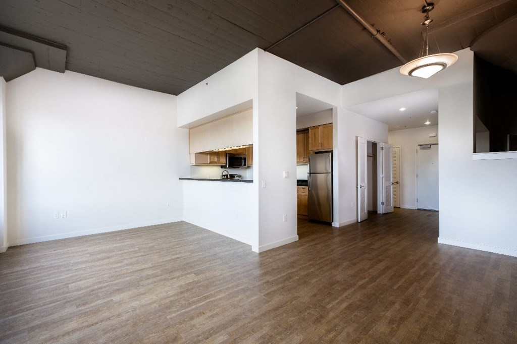 an empty living room with white walls and a wood floor