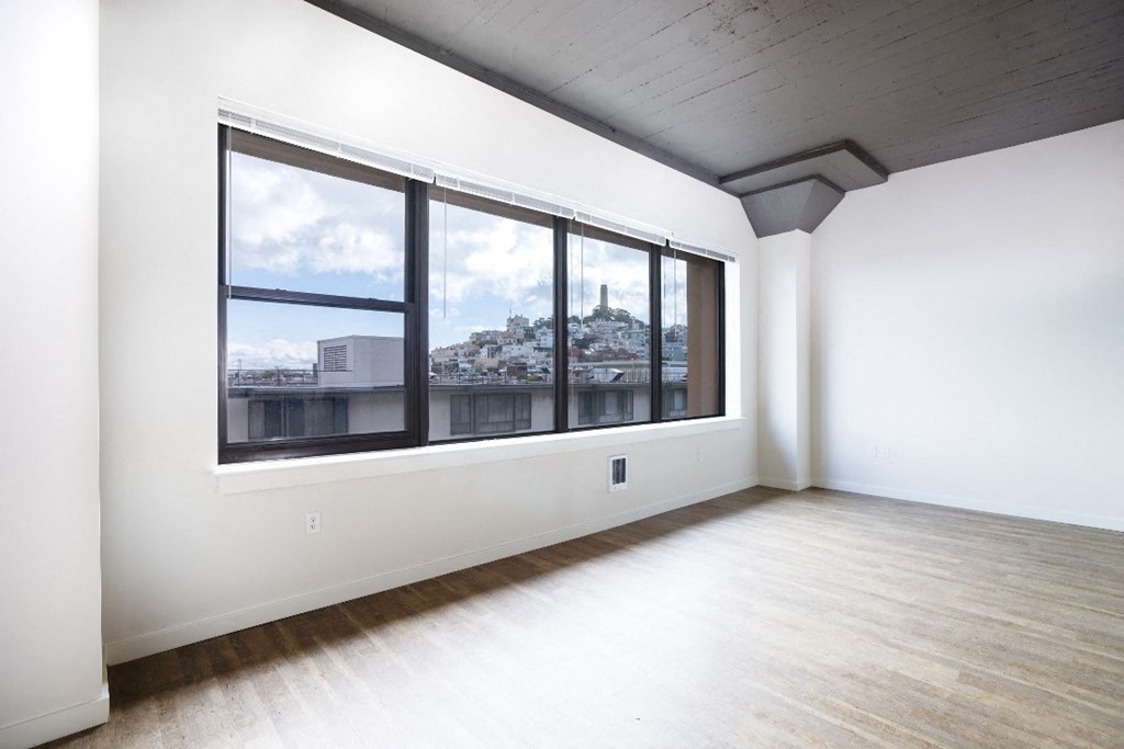 an empty living room with large windows and a city view