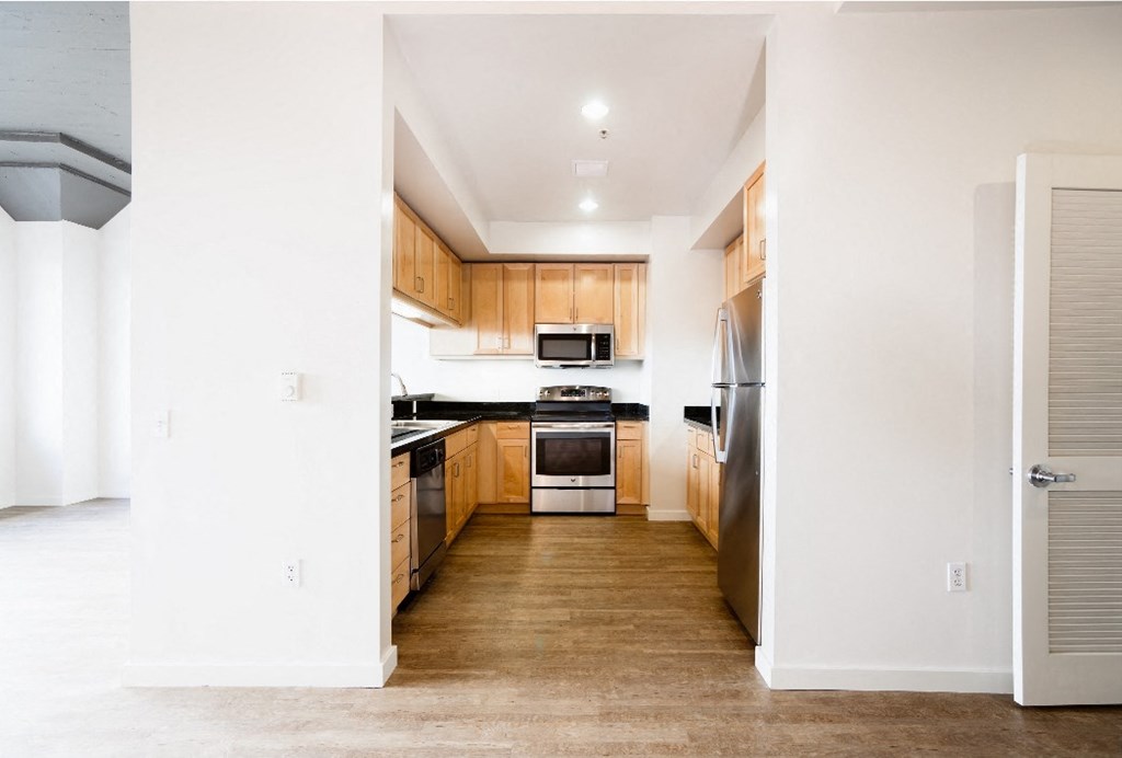 an empty kitchen with wood floors and wooden cabinets