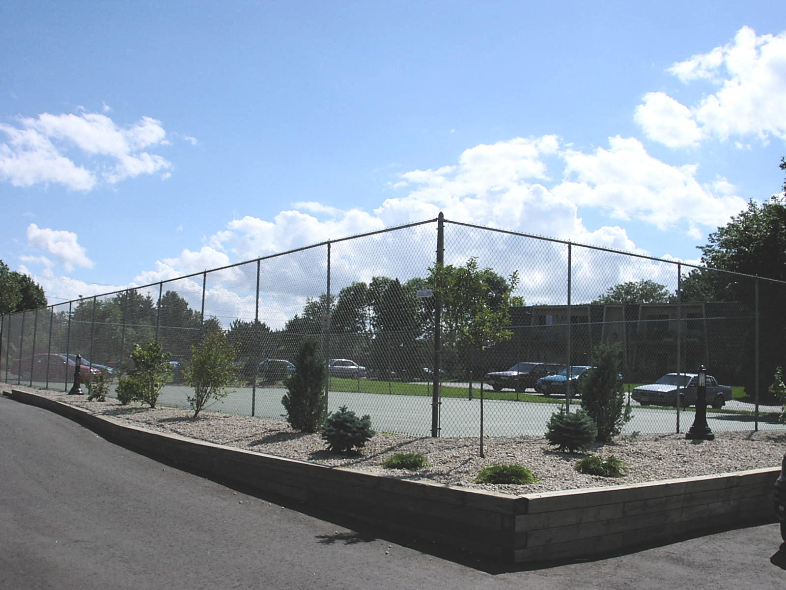 a view of a parking lot behind a chain link fence