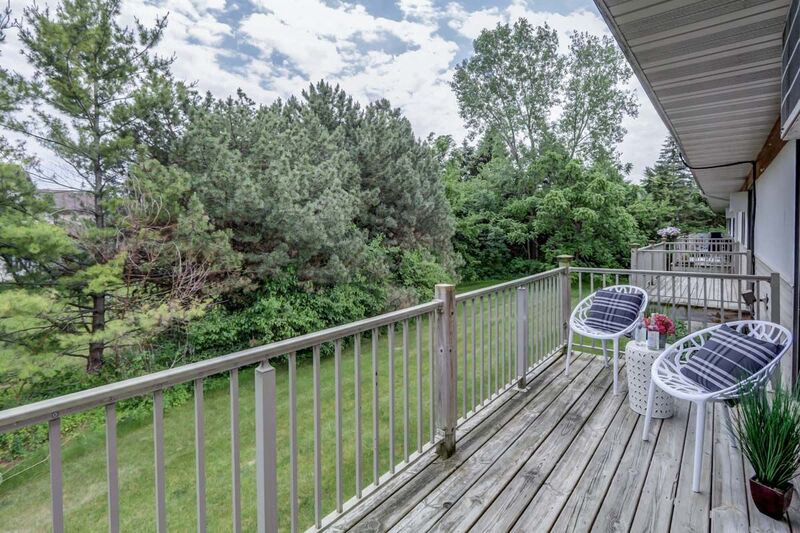 a balcony with two blue chairs and a yard with trees
