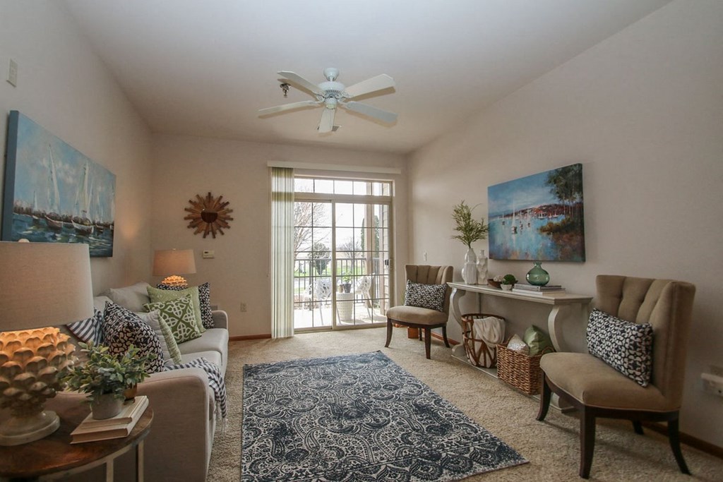 a living room with a ceiling fan and a door to a balcony