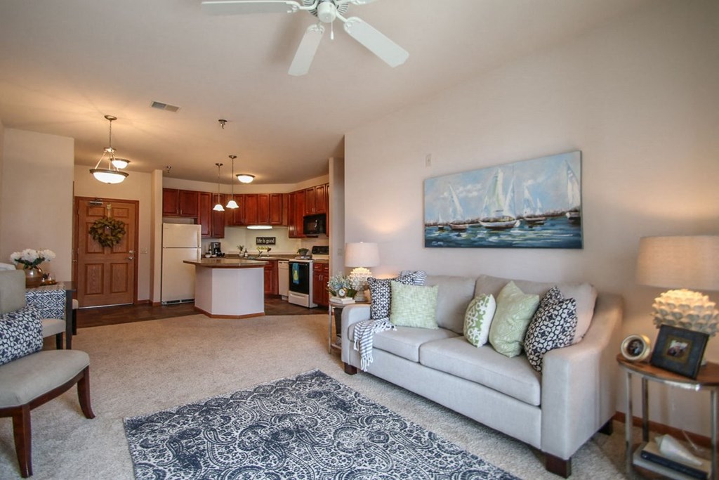 a living room and kitchen with a couch and a ceiling fan